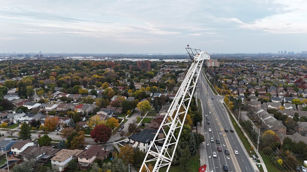 Looking along the crane's white lattice jib, high above the boulevard and the rooftops of the neighbourhood.